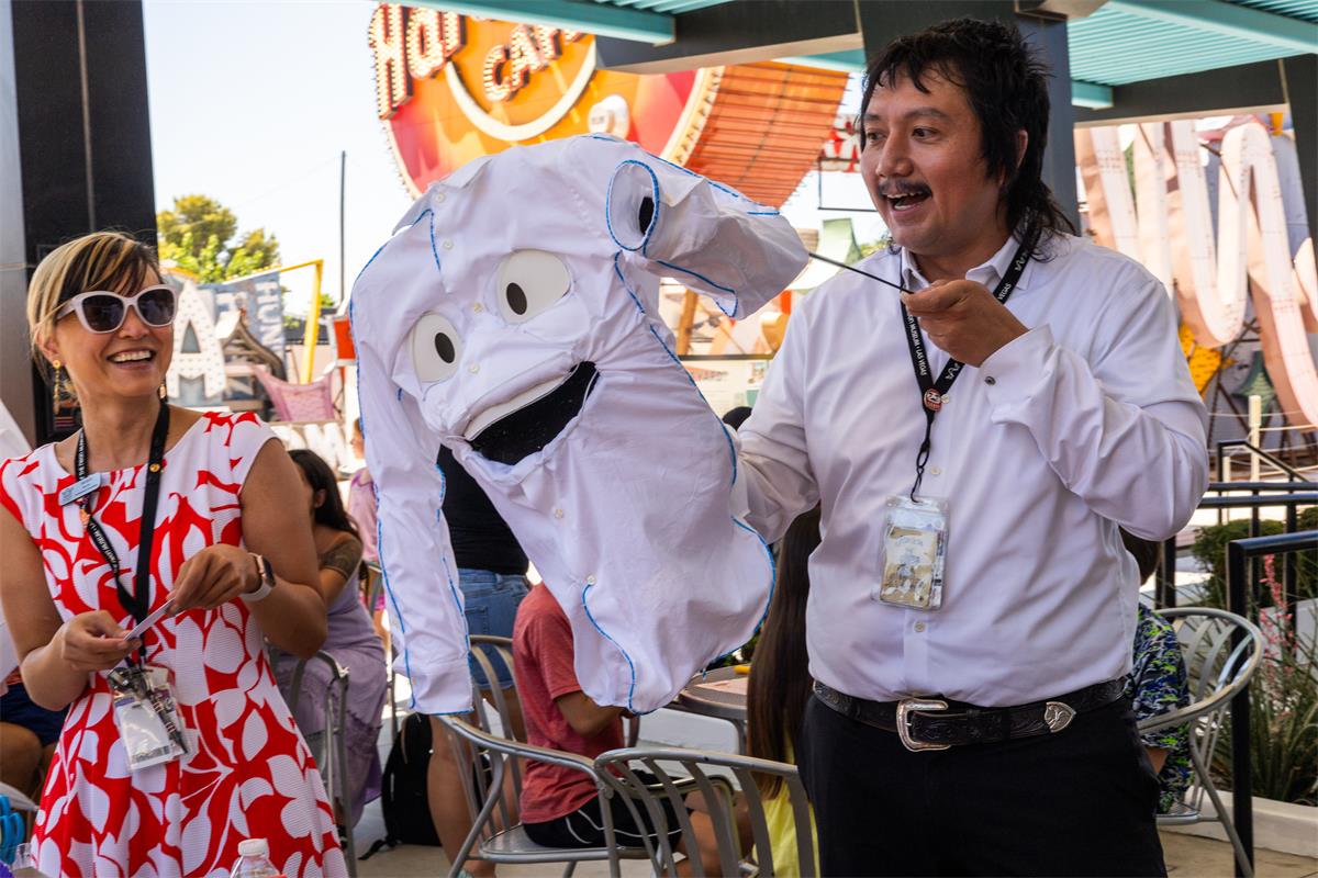 Leading a craft table, while my colleague, Doug, shows kids a puppet of our Happy Shirt sign.